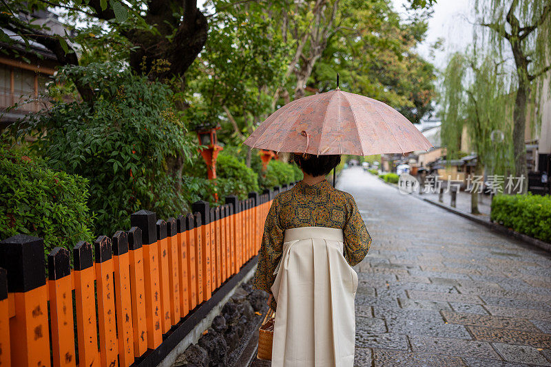 穿着和服/袴的年轻女子在下雨天走在城里——后景